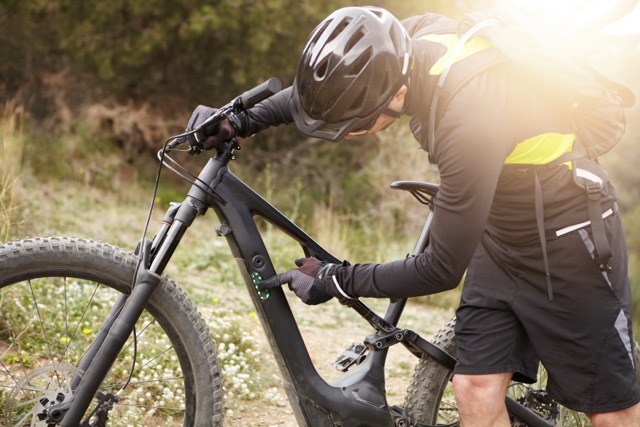 adult riding electric bicycle outdoors in nature